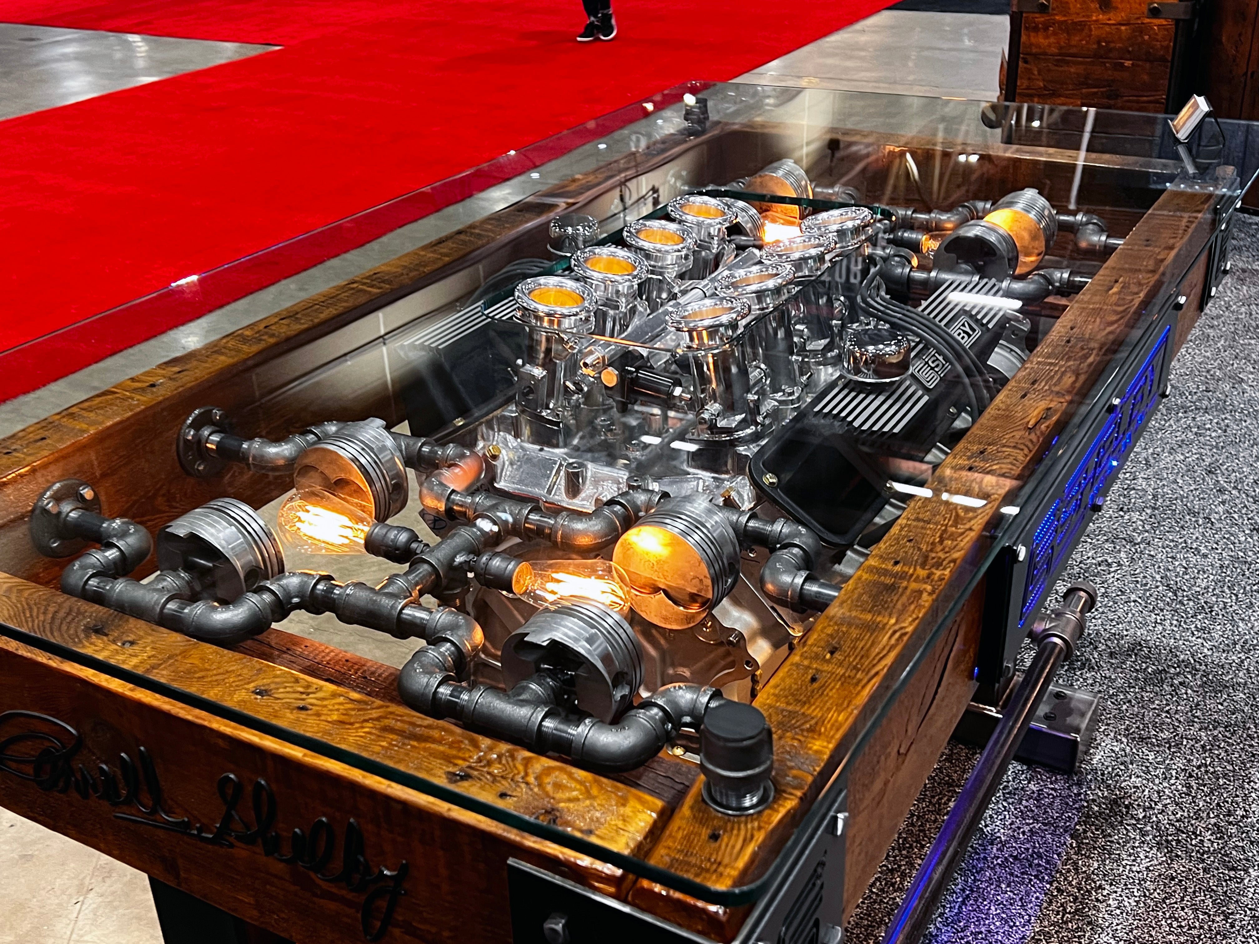 steampunk industrial table with automotive engine on display within glass